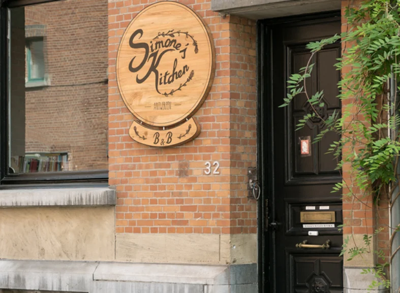 The front door of Simone's Kitchen at Breughelstraat 32, Antwerp, with its wooden sign.